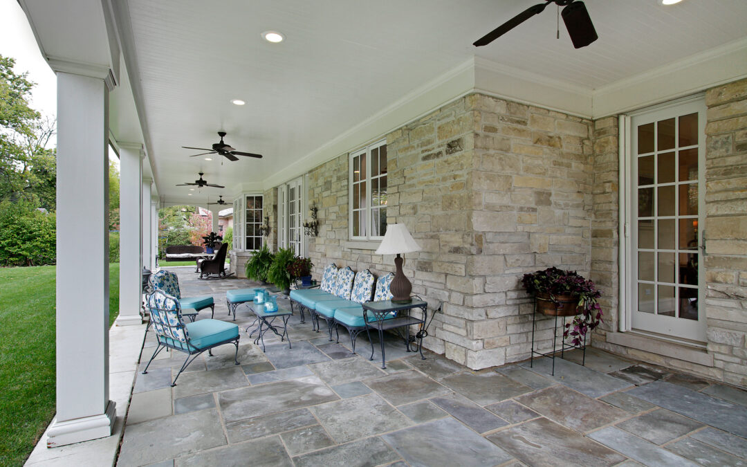 Bluestone patio landscaping with seating and stone walls on the exterior of the house
